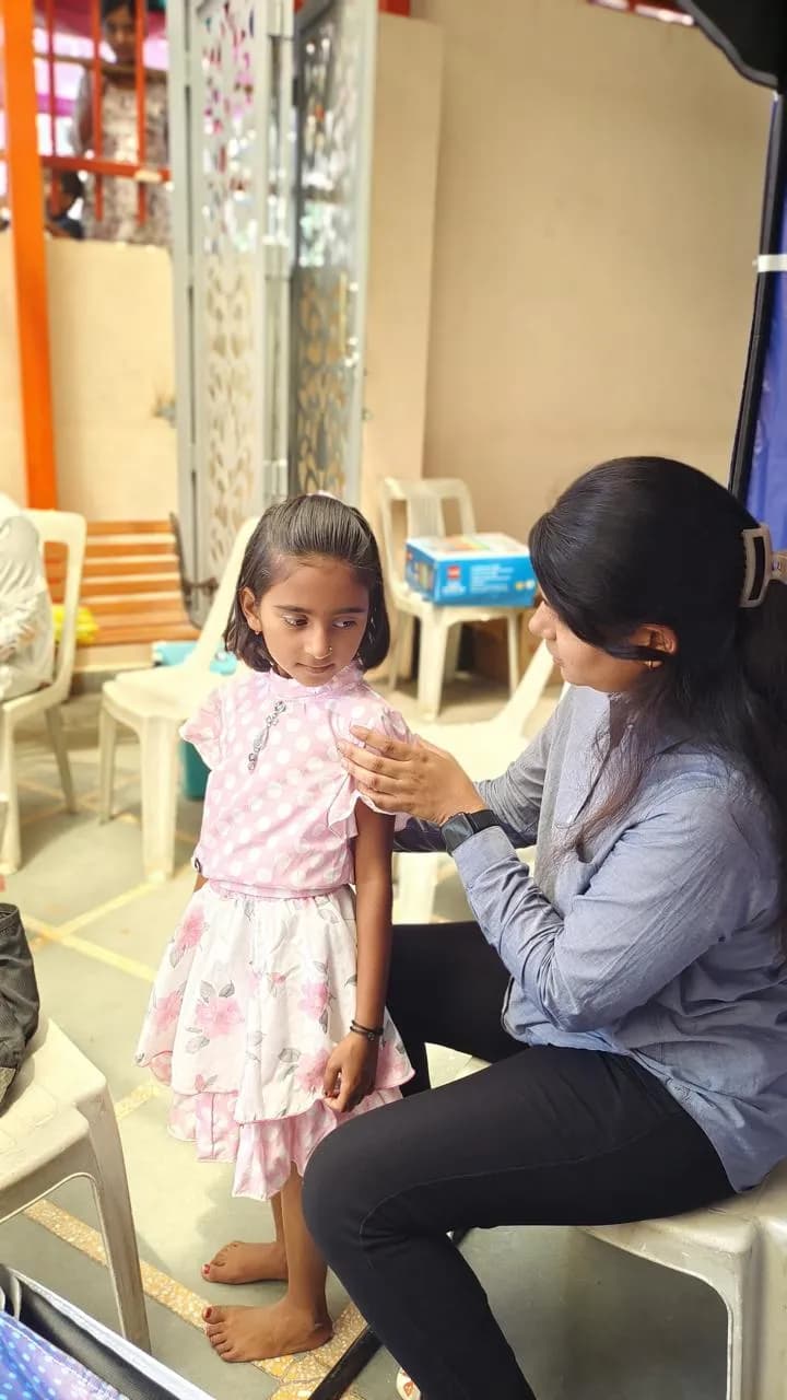 Therapist examining a child's arm at an outreach camp