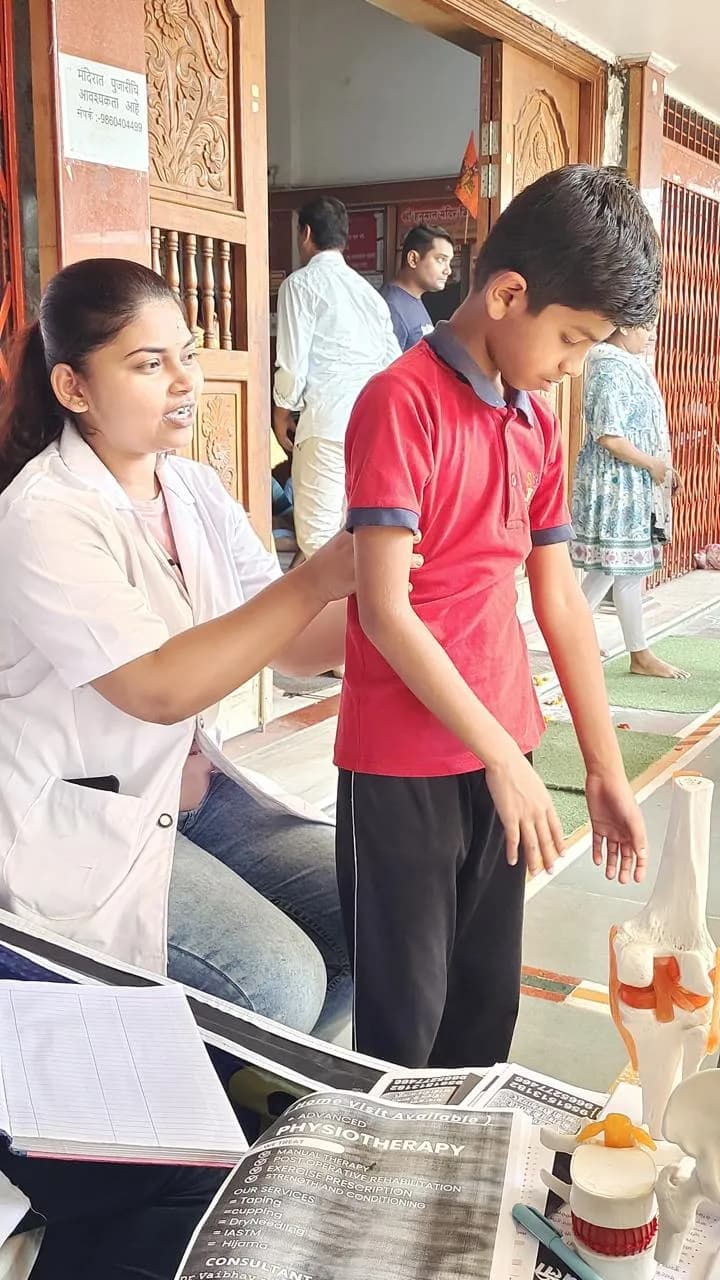 Physiotherapist checking a boy's posture and arm movement at a temple camp